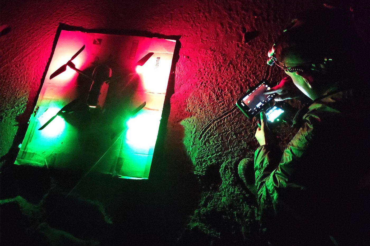 Un dron preparado para despegar de noche, iluminado con luces rojas y verdes